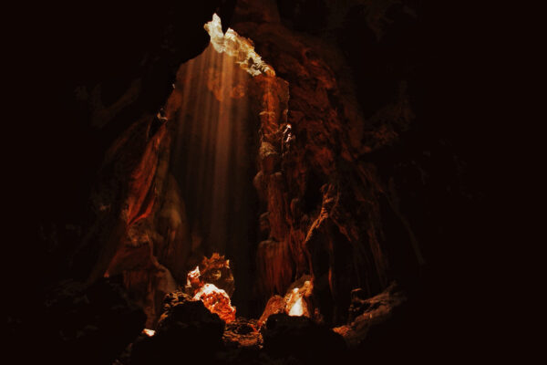 In a cave with light coming through a crack in the ceiling.