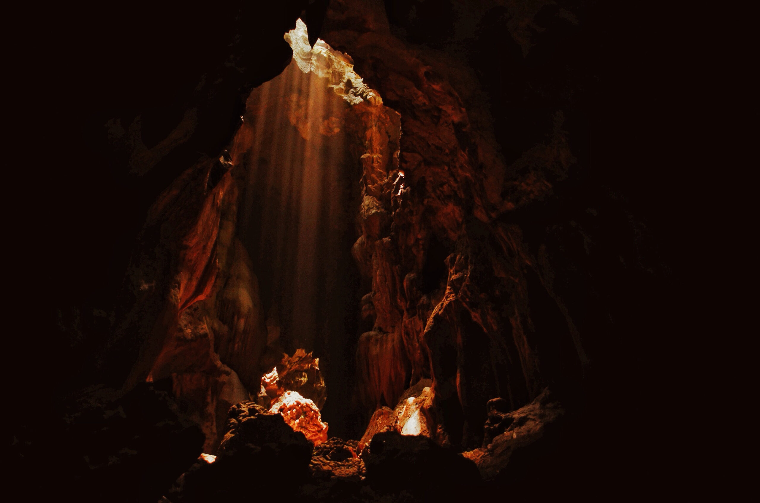 In a cave with light coming through a crack in the ceiling.