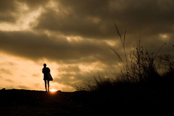 Silhouette of a person walking with sunset
