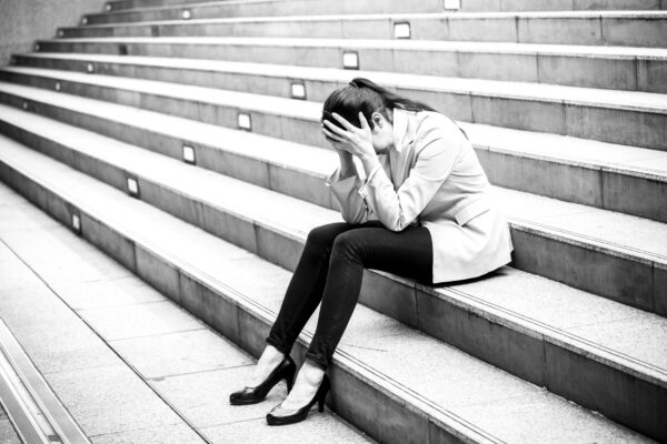 Businesswoman sitting on stone stairs, feeling in pain