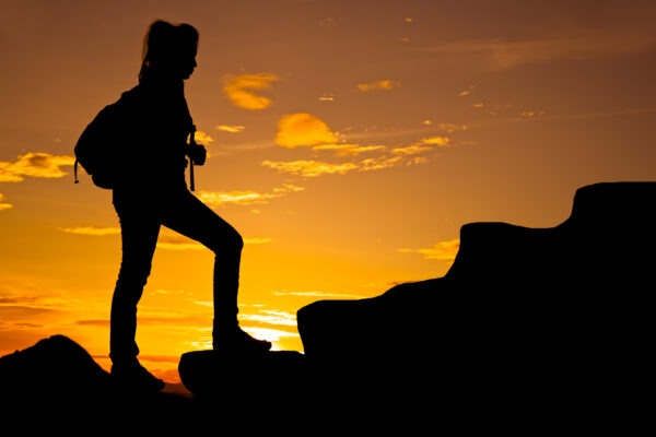 Woman walking on top of mountain at twilight.