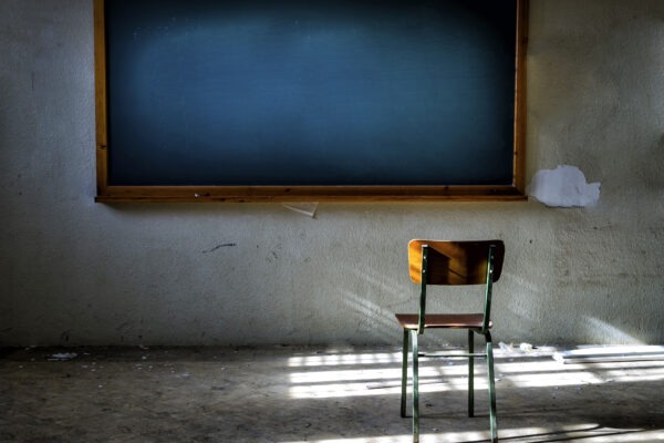Abandoned classroom with chair in front of the vintage blackboard